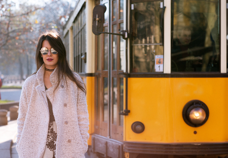 Attractive young woman wearing gray coat with long dark hair and sun glasses posing outdoor in Milan streets, Italy. Beautiful caucasian model portrait.の写真素材