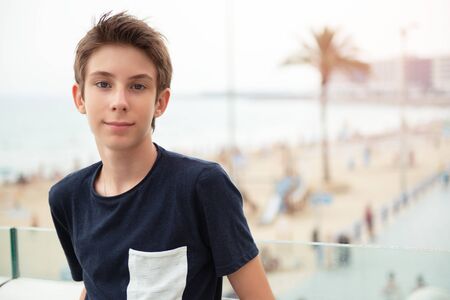 Handsome young boy looking at camera over panorama of Alicante. Beautiful calm smiling teen boy at...