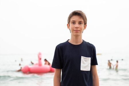 Handsome young boy at beach in Alicante. Beautiful calm smiling teen boy at Mediterranean sea coast...
