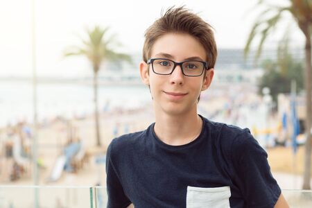 Handsome young boy wearing glasses looking at sea over panorama of Alicante. Beautiful calm smiling teen boy at Mediterranean coast in Spain. Travel, summer vacation, tourism, teenage lifestyle.の写真素材