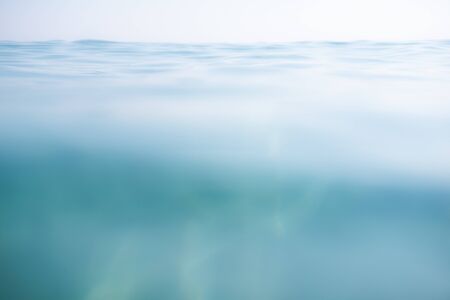 Blue calm sea with waves and rays of sunlight shining through, on the water surface and underwater....