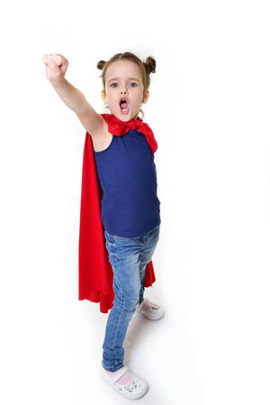 Adorable little girl flying like a superhero in blue t-shirt and red mantle. Super girl. The new generation saves the world. Good triumphs over evil. Funny kid portraitの写真素材