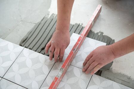 Tiler laying the ceramic tile on the floor. Professional worker makes renovation. Construction....