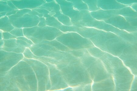 Underwater. Sun glare at the bottom of the sea. Waves underwater and rays of sunlight shining...