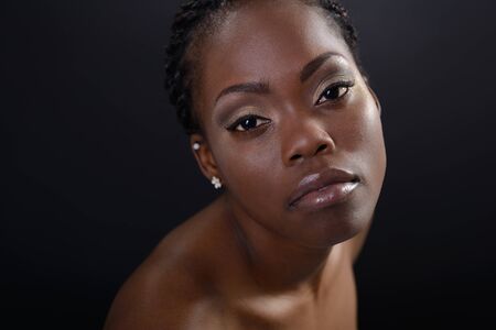 Beautiful young african american woman looking at camera, over dark background. Beauty portrait of...