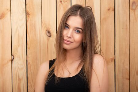 Charming young woman. Beautiful smiling girl, indoor portrait over wooden backgroundの写真素材