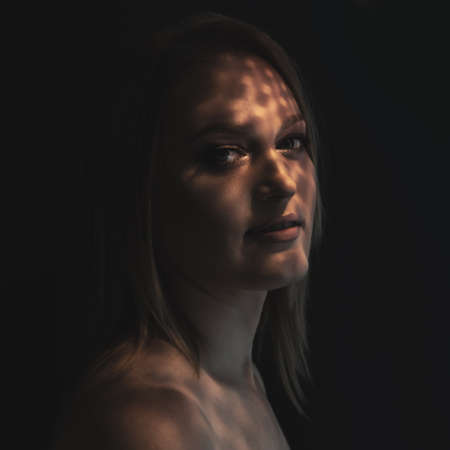 Beautiful mid adult woman with interesting pattern of light and shadow on her face. Beauty female portraitの写真素材