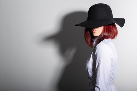 Mysterious fashion young woman in black hat and white shirt, copy space where can the advertising message be writtenの写真素材