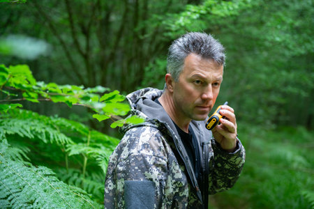 Mature man walking and hiking in mountain forest and using radio set. Male spring outdoor portrait.の写真素材