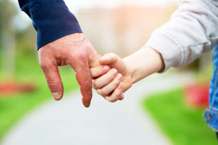 Hands. Father's and his son hands. Dad leading son over summer nature outdoor. Male and children hands closep. Family, trust, protecting, care, parenting concept.の写真素材