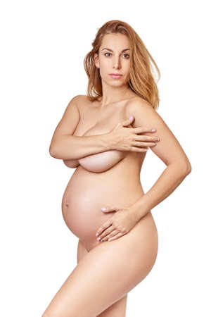 Pregnant woman with big belly posing at studio over white background. Pregnancy.の写真素材