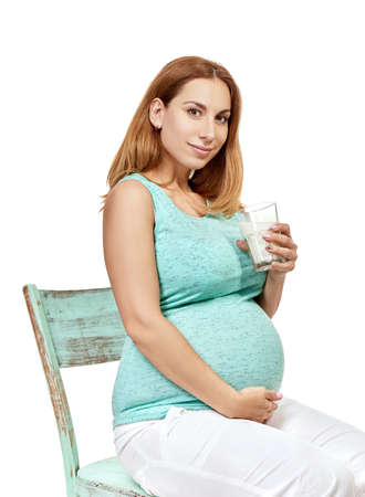 Pregnant woman. Portrait of pregnant lady drinks milk in studio over white background. Healthcare, healthy eating, pregnancy, prenatal concept.の写真素材