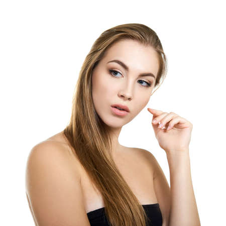 Young attractive woman with perfect make-up and long fair hair posing and smiling at studio over white background, beauty female portrait.の写真素材