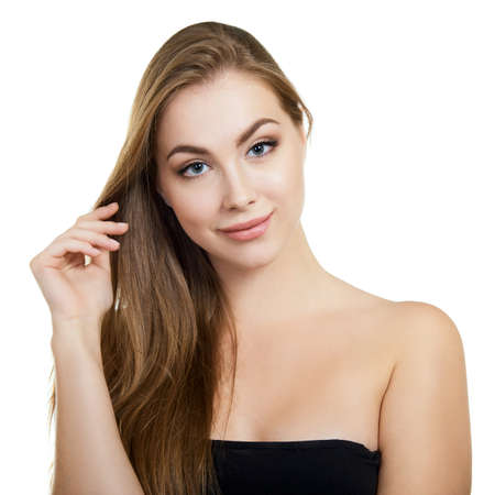 Young attractive woman with perfect make-up and long fair hair posing and smiling at studio over white background, beauty female portrait.の写真素材