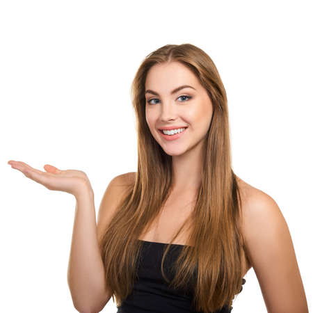 Young attractive woman with perfect make-up and long fair hair smiling and pointing with her hand at copy space at studio over white background, beauty female portrait.の写真素材