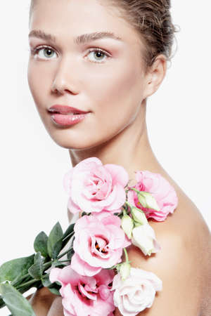 Portrait of a beautiful young woman with clean skin, soft day makeup and pink flowers, beauty treatment, cosmetology and anti-aging themeの写真素材
