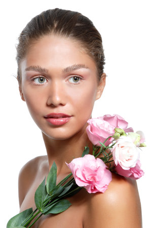 Portrait of a beautiful young woman with clean skin, soft day makeup and pink flowers, beauty treatment, cosmetology and anti-aging themeの写真素材