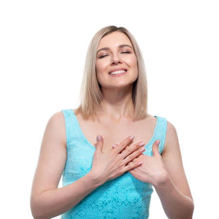 Pretty woman with hands on chest and grateful gesture on face, feels hopes for successful plan realization, believes in success, wishes dream come true, visualizes future.の写真素材