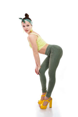 Young fashion charming girl wearing streetwear and yellow high heel sandals dancing at studio on a white backgroundの写真素材