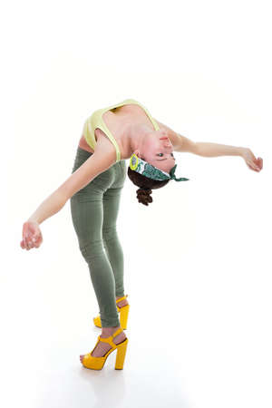 Young fashion charming girl wearing streetwear and yellow high heel sandals dancing at studio on a white backgroundの写真素材