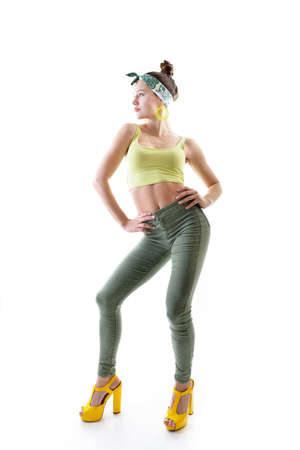 Young fashion charming girl wearing streetwear and yellow high heel sandals dancing at studio on a white backgroundの写真素材