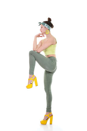 Young fashion charming girl wearing streetwear and yellow high heel sandals dancing at studio on a white backgroundの写真素材