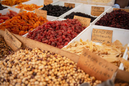 Spices, dried chestnuts, nuts, candied fruit, salted olives are solding at outdoor market, Sicily,...