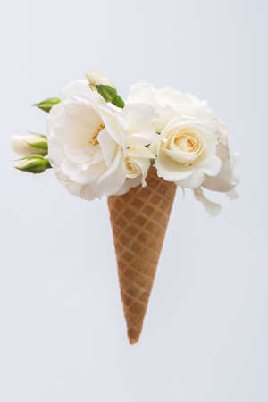 Ice cream waffle cone with a bouquet of summer flowers white roses. Diet and thinking outside the box design conceptの写真素材