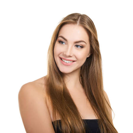 Young attractive woman with perfect make-up and long fair hair posing and smiling at studio over white background, beauty female portrait.の写真素材