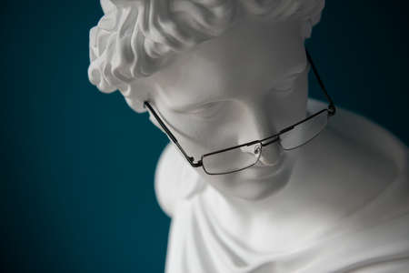 Plaster statue head with glasses. Antiquity and modernity. Myopia and hyperopia treatment conceptの写真素材