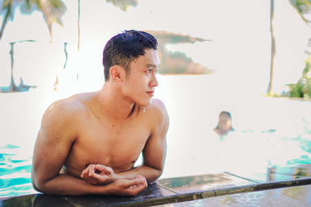 Handsome asian men having fun at swimming pool under sunlight