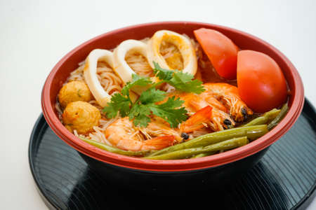 Bowl of rice noodles with cuttle and shrimp and tomato isolated on white background