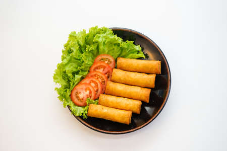 Spring rolls with tomato slice and salad on plate isolated on white background