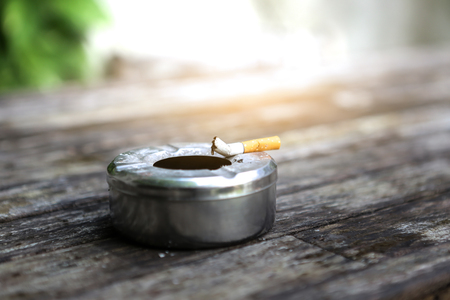 Ash tray on wood table with orange lightの写真素材
