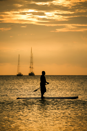 Silhouette Man with paddle on surfboard sunset momentの写真素材