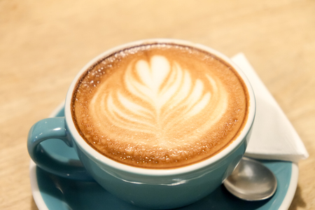 A cup of coffee Latte art green glass on wood tableの写真素材