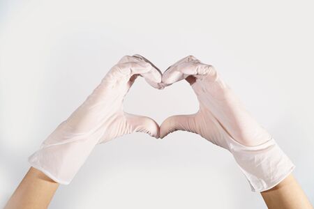Woman hands wering rubber glove protection safety covid 19 white background heart gestureの写真素材