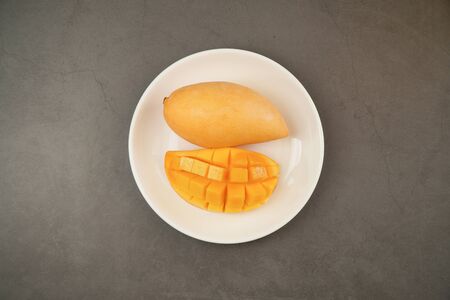 Fresh Mango on white plate and black pattern background