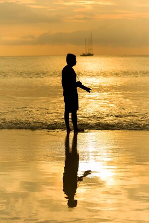 Man photographer act shooting with landscape sea sunset backgroundの写真素材