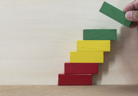 Concept of building success foundation. Hand put red puzzle wooden blocks in the shape of a...