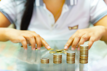 Saving money, woman stacking coins into increasing columns.の写真素材
