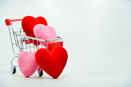 Red and Pink hearts in mini shopping cart falling on the background for valentines day. Top view and copy space.の写真素材