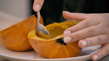 Girl picks boiled pumpkin with a spoonの写真素材