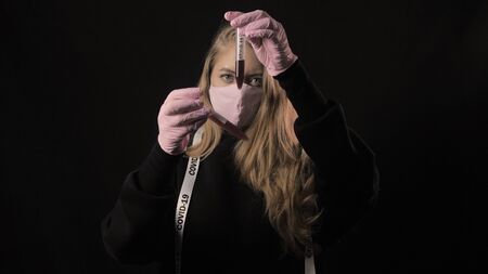 Girl in a pink mask holds a test tube with blood and the inscription covid-19 and twists the mask....