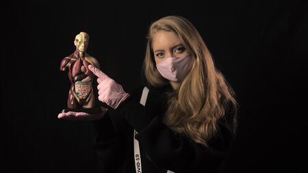Girl in a pink mask and a ribbon with the inscription covid 19 points to the lungs on the anatomical...
