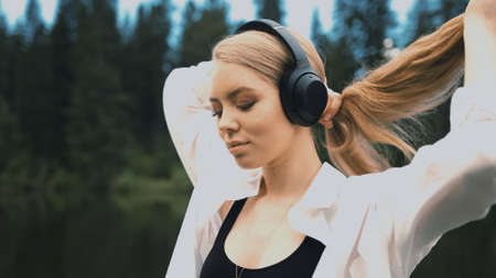 TOMSK, RUSSIA - May 23, 2020: Beautiful young blonde woman with natural appearance listening to...