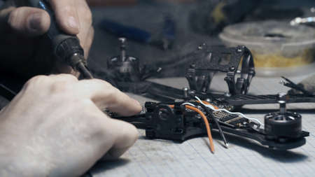 Guy soldering drone FPV wires. Back frame viewの写真素材