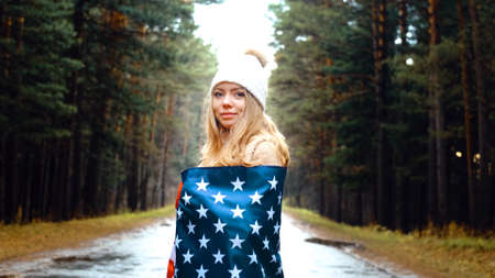 Girl in a hat took refuge in the flag of America. USA