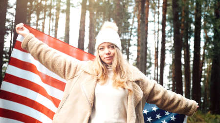 Girl in a hat took refuge in the flag of America. USAの写真素材