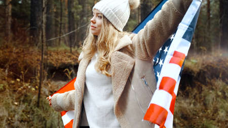 Girl in a hat took refuge in the flag of America. USA